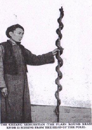 A Ch'iang priest holding a rod with a brass serpent wound around it