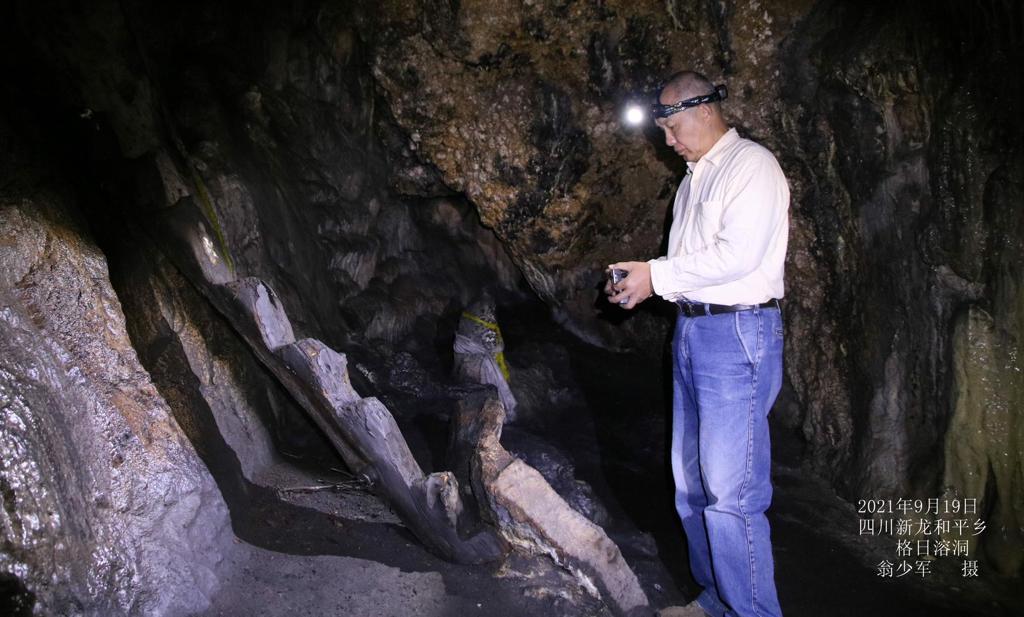 A man with a headlamp standing inside a dark cave